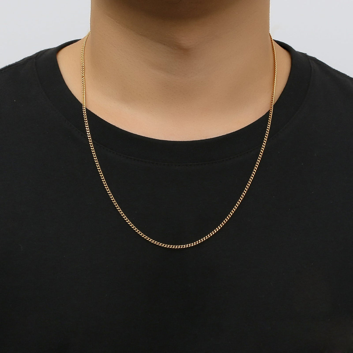 2mm Cuban gold chain worn on neck over black shirt