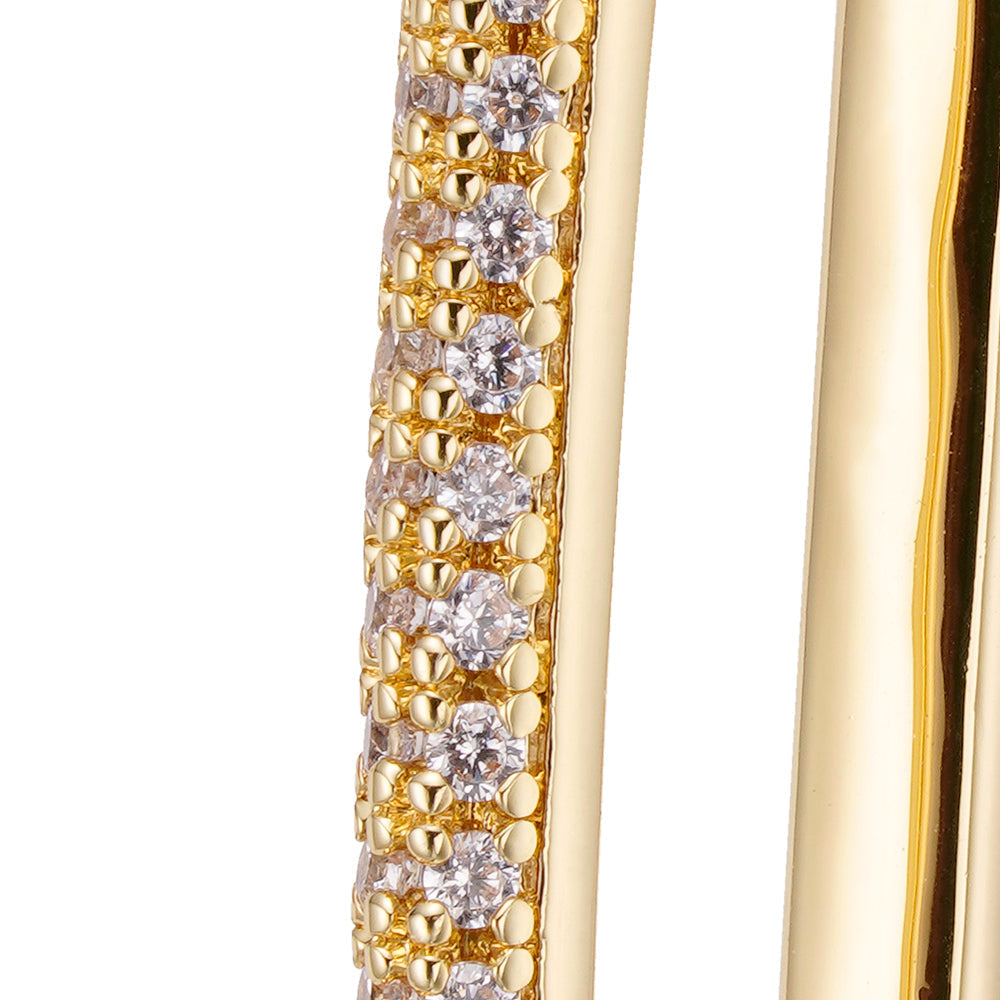 Close-up detail of iced out cubic zirconia crystals on gold oval loop earring