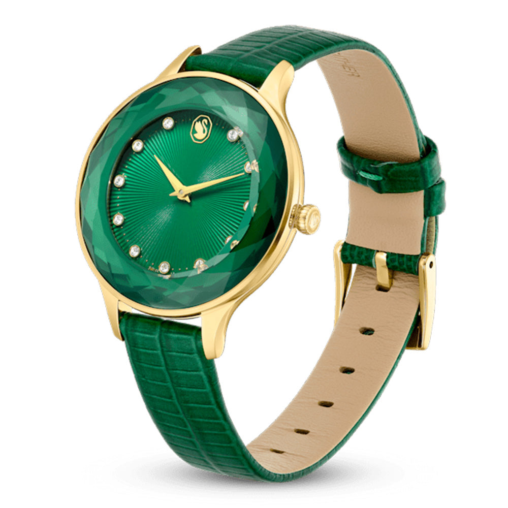 Swarovski Octea Nova watch on wrist showing green dial, gold case, and crocodile-texture green leather strap